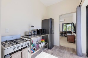 Una cocina compacta con estufa a gas, tostadora, licuadora y refrigerador.