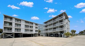 A multi-story building with balconies and a parking area. - Whispering Sands II 204 - Second Row Complex (Oceanview unit) in Garden City Beach (Garden City Beach)