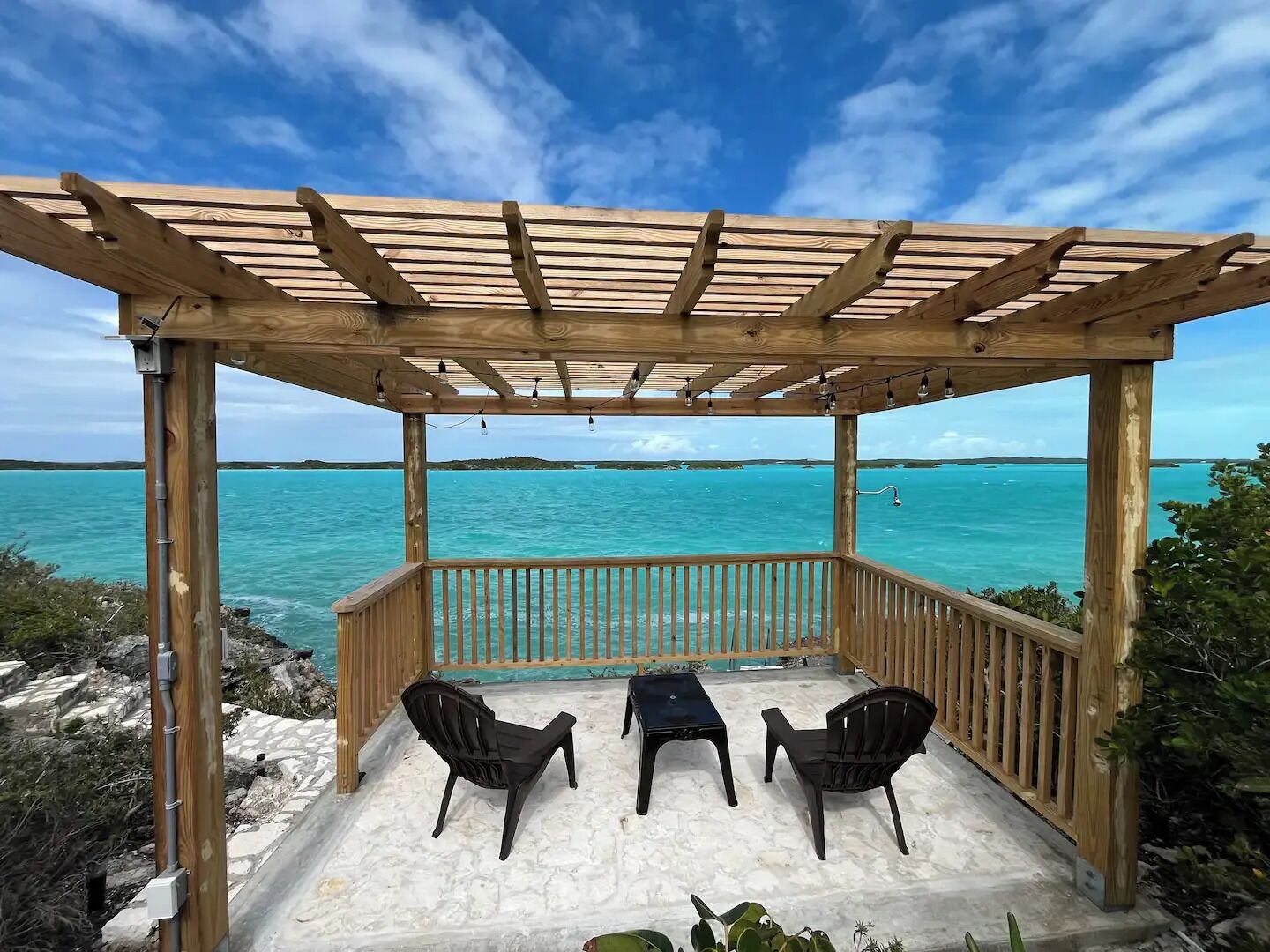 Ein hölzerner Pavillon mit Blick auf türkisfarbenes Wasser und einen klaren Himmel.