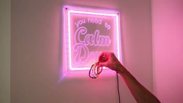 Ein Neonlichtschild mit dem Text 'you need to Calm Down' an einer weißen Wand.