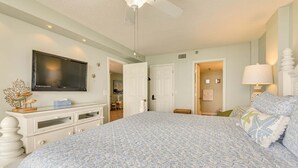 A bedroom with a bed, a TV, a ceiling fan, a dresser, and a lamp. - Emerald Surf 204 (Navarre)