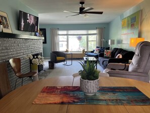 Ein Wohnzimmer mit Kamin, einer Couch, einem Esstisch und einem Fernseher.