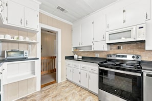 A kitchen with white cabinets, a microwave, a stove, and a toaster.