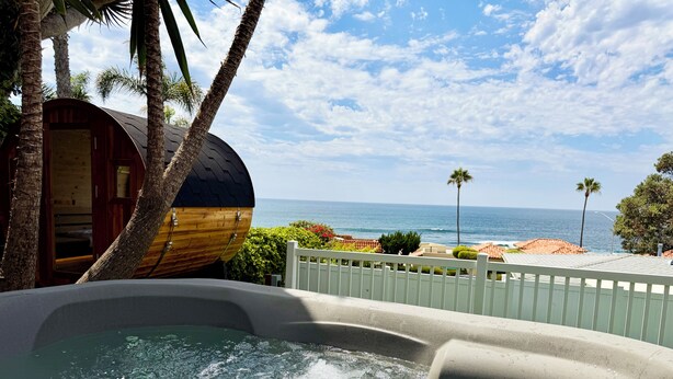 Boblebad med udsigt over havet, en trækonstruktion og et hvidt hegn.