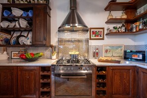 A kitchen with a stove, oven, and wine rack. - Villa Palazzolo 8, Emma Villas (Anghiari)