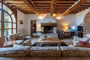 Una sala acogedora con chimenea, vigas de madera y asientos cómodos.