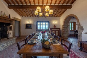 Comedor con mesa de madera dispuesta para seis personas, rodeado de paredes de piedra y un techo abovedado.