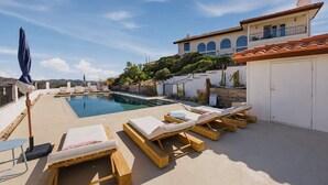 A pool area with lounge chairs and a wooden deck. - Desert Sunsets Wellness Villa - Pool, Sauna, Spa, Pool Table, Firepit, Yoga, Steam Room & Stunning Views (Yucca Valley)