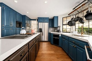 Una cocina moderna con armarios azules, electrodomésticos de acero inoxidable y piso de madera.