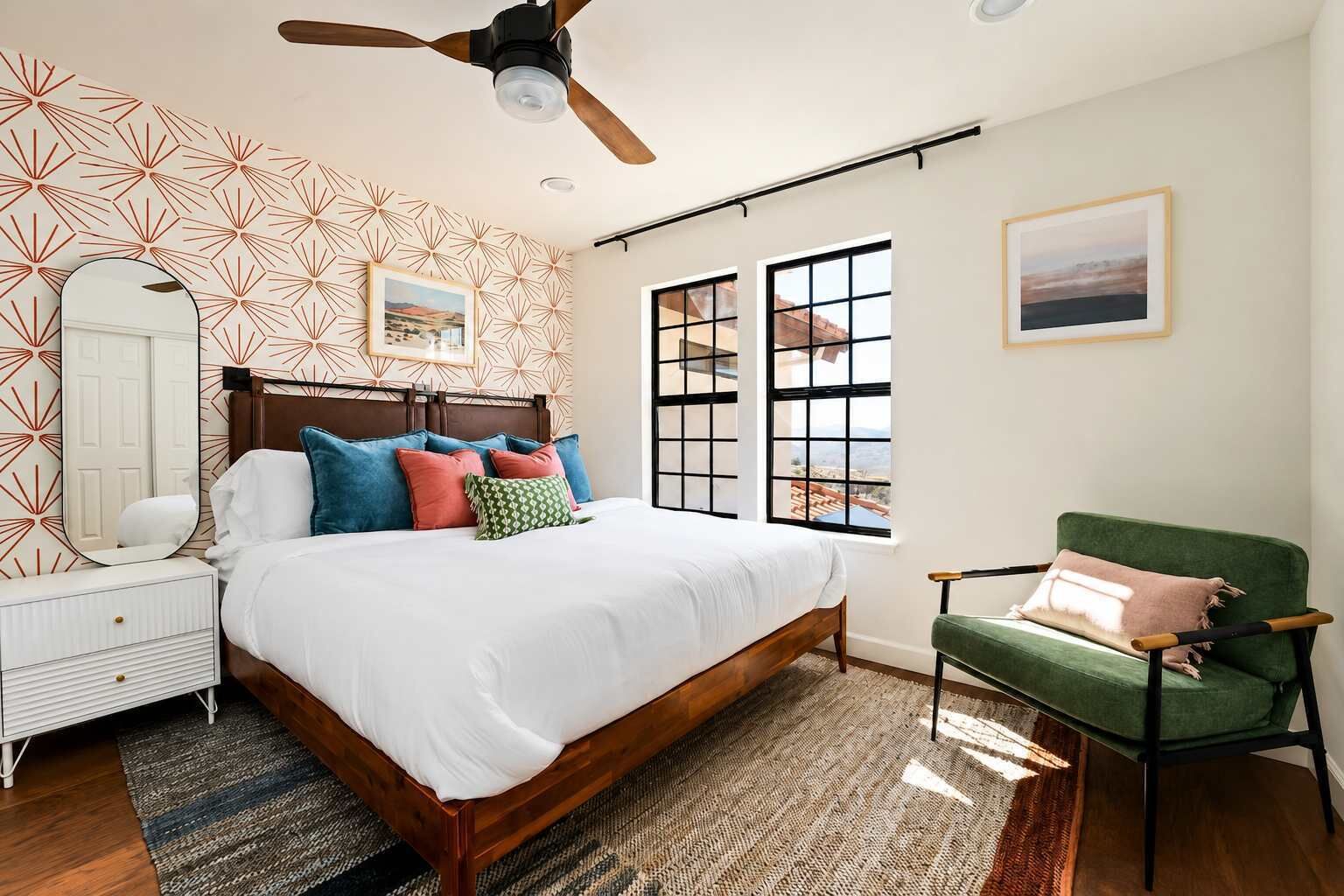 A bedroom with a bed, a chair, a dresser, a mirror, and a ceiling fan.