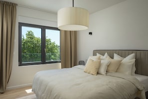 Ein Schlafzimmer mit einem großen Bett, einem Fenster mit Vorhängen und einer Pendelleuchte.