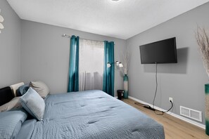A bedroom with a bed, curtains, a TV, and a vase. - Cozy Townhome Near Downtown & Target Field (Minneapolis)