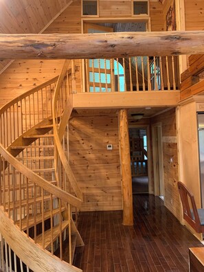 A wooden interior with a spiral staircase, wooden walls, and a dark wooden floor.