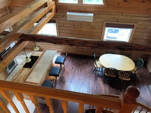 A cabin with a dining area, a kitchen, and a loft space.