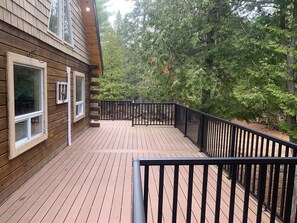 A wooden deck with black railings, surrounded by trees.