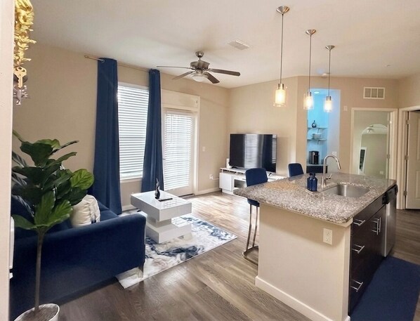 Un apartamento moderno con isla de cocina, comedor, sala de estar con sofá y ventilador de techo.
