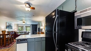 A modern kitchen with a black refrigerator, a stove, and a microwave. - Lake Fork Ski-In Creekside w Gas Stove, Parking (Taos Ski Valley)