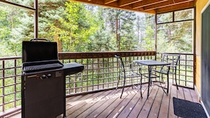 A covered outdoor deck with a grill, a table, and chairs. - Lake Fork Ski-In Creekside w Gas Stove, Parking (Taos Ski Valley)