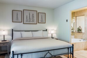 A bedroom with a bed, two bedside tables with lamps, a nightstand, and a large mirror. - Lake Fork Ski-In Creekside w Gas Stove, Parking (Taos Ski Valley)