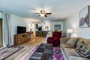 A living room with a television, wooden furniture, a red armchair, and a patterned rug. - Lake Fork Ski-In Creekside w Gas Stove, Parking (Taos Ski Valley)