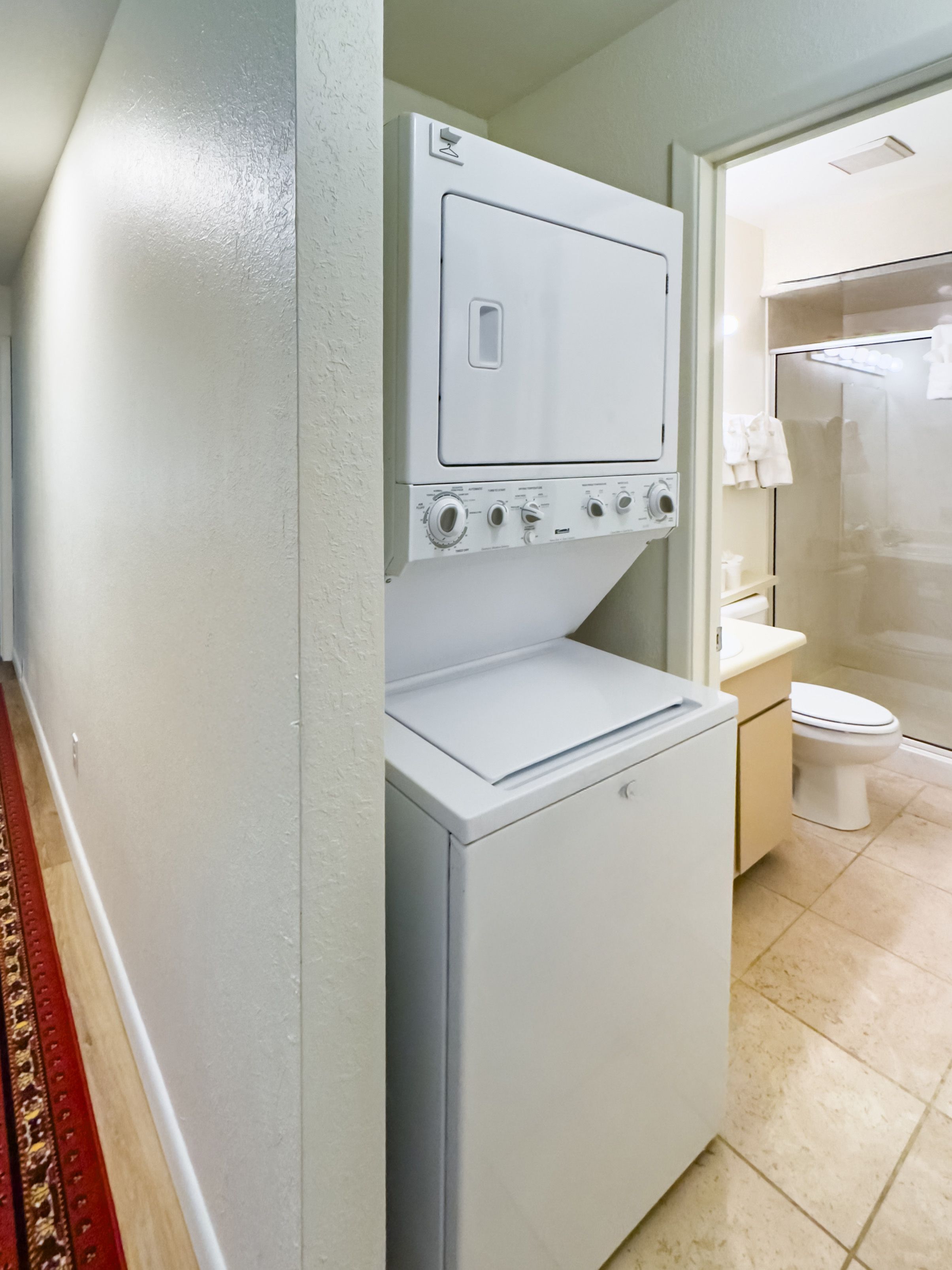 Ein kleiner Hauswirtschaftsraum mit Waschmaschine und Trockner, Toilette sowie Duschbereich.