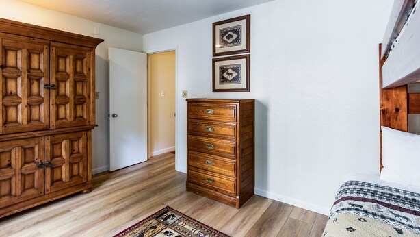 A room with a wooden wardrobe, a dresser, and a patterned rug. - Lake Fork Ski-In Creekside w Gas Stove, Parking (Taos Ski Valley)