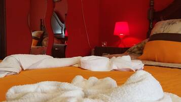 A hotel room with a bed, towels, a heart-shaped light, and a lamp.
