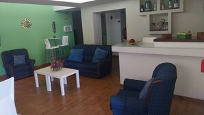 A modern living room with a sofa, chairs, a coffee table, and a bar area with bottles.