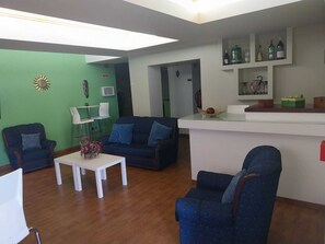 Un salon moderne comprenant un canapé, des fauteuils, une table basse et un coin bar avec des bouteilles.