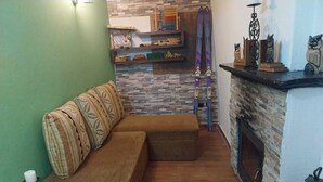 A cozy living room with a brown sofa, a fireplace, and a stone wall.