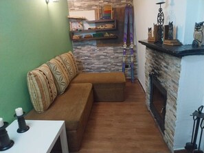 Un salon chaleureux avec un canapé marron, une cheminée et un mur en pierre.