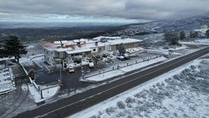 Un edificio con estacionamiento, una carretera y un paisaje nevado.
