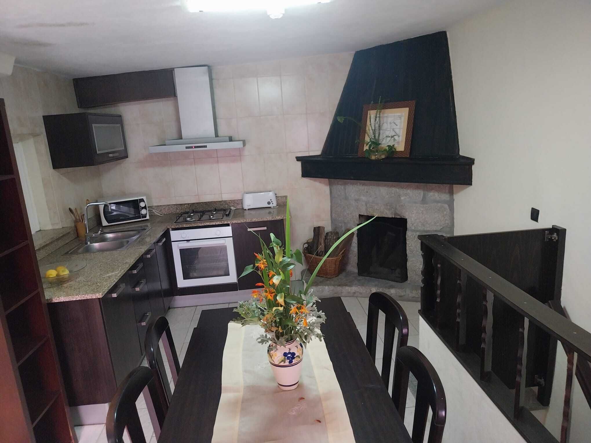 A kitchen with a dining table, chairs, a microwave, an oven, a toaster, a gas stove, a chimney, and a fireplace.
