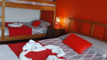 A room with a bunk bed, a single bed with red pillows, and a wall with a framed picture.