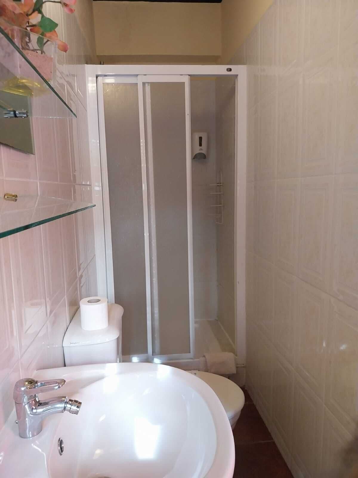 Een badkamer met een wit wastafelmeubel, toilet en douchecabine.