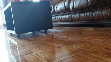 Una habitación con piso de madera, un sofá de cuero marrón y un mueble negro.