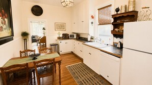 A compact kitchen with white cabinets, a dining table with chairs, a hanging light fixture, and a window with blinds. - Walk to Downtown Long Term Rental with Wifi, Grill, Yard (Durango)