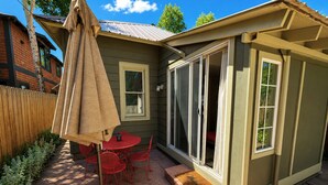 A patio with a table and chairs, a covered umbrella, and a wooden fence. - Walk to Downtown Long Term Rental with Wifi, Grill, Yard (Durango)