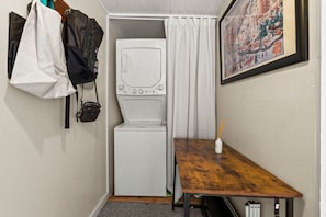 Ein kleines Zimmer mit Waschmaschine, einem kleinen Tisch und einem Bild an der Wand.