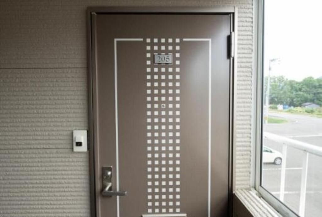 Puerta con teclado numérico y vista a un estacionamiento a través del ventanal.