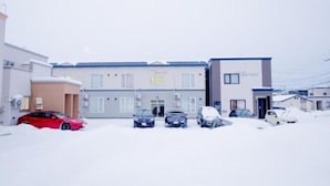Un bâtiment doté de nombreux espaces de stationnement, une voiture rouge et un sol recouvert de neige.