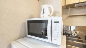 Een witte magnetron op een wit aanrecht, met een roestvrijstalen spoelbak en kasten op de achtergrond.