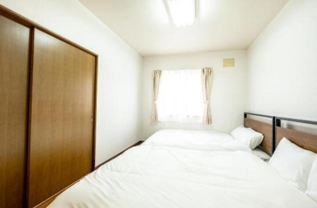Habitación de hotel con cama, armario y ventana con cortinas.