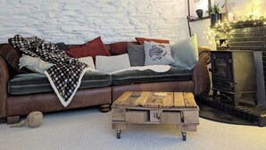 Un salon chaleureux avec un mur en pierre, un canapé en cuir marron, une table basse en bois et une cheminée.