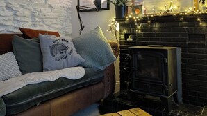 Un salon chaleureux avec un mur en pierre, une cheminée, un canapé avec des coussins et une table basse.
