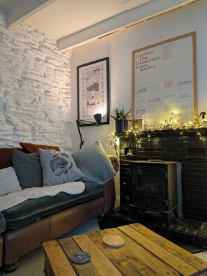 Ein gemütliches Wohnzimmer mit Steinwand, Kamin, einer Couch mit Kissen und einem Couchtisch.