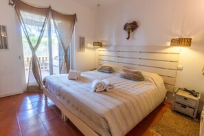 Ein Schlafzimmer mit Bett, Vorhängen, Kopfteil, Nachttisch und Beistelltisch.