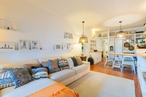 Ein gemütliches Wohnzimmer mit einer Couch, einem Essbereich mit Tisch und Stühlen sowie einer Küche im Hintergrund.