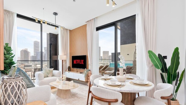 Een moderne woonkamer met een grote televisie, een eettafel en zitplaatsen.
