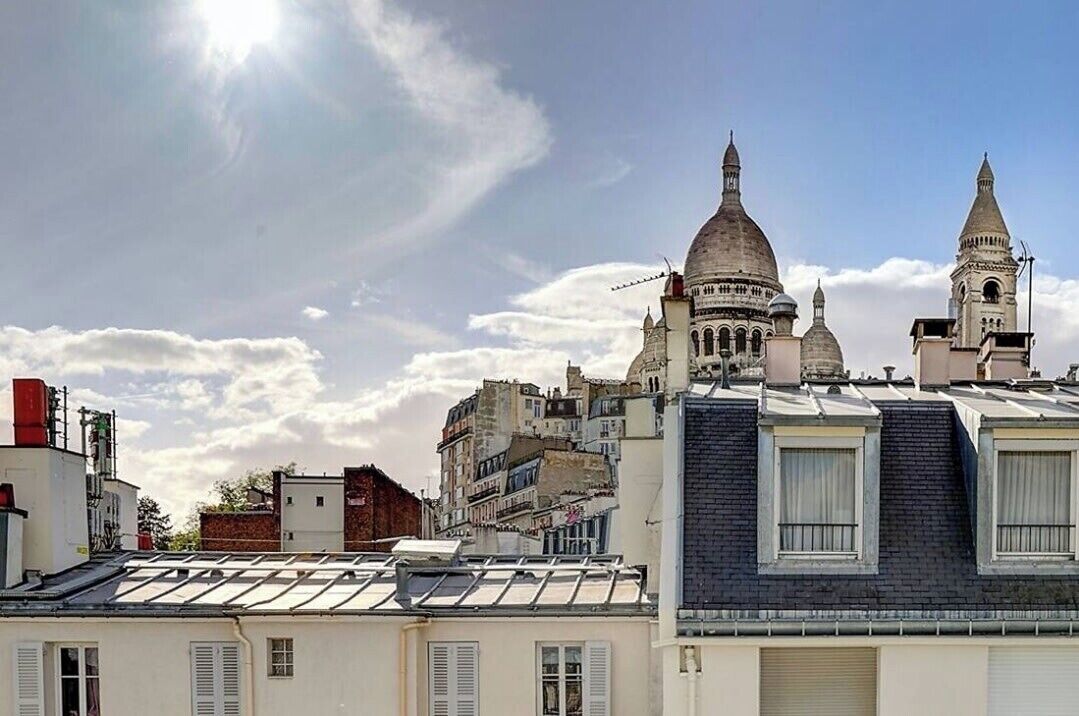 Un paisaje urbano con arquitectura histórica, incluyendo edificios con cúpulas y un campanario, bajo un cielo despejado.
